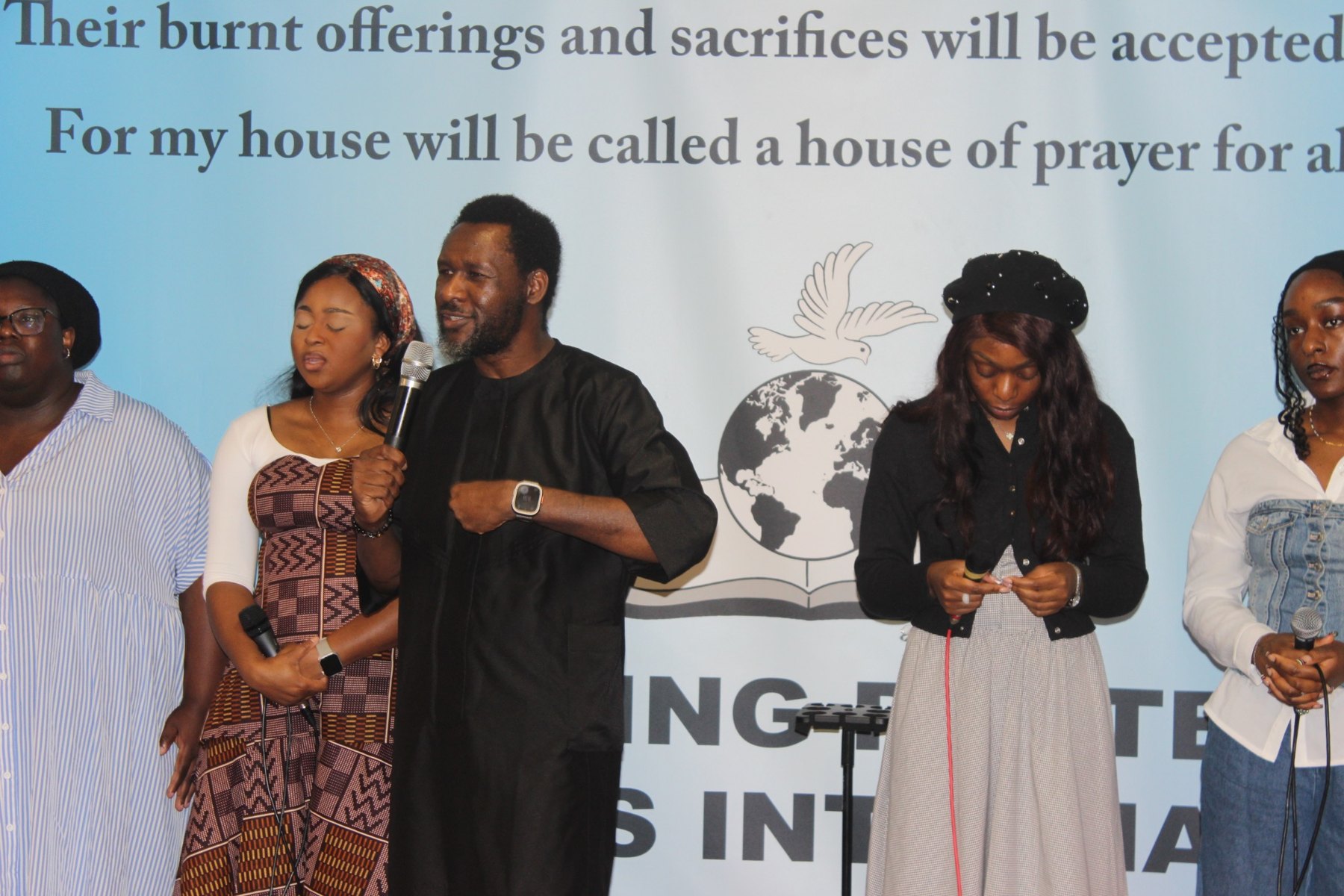 Members of the SWPM worship team standing together at the front of the church